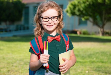 Photo for Smiling school student wit backpack book. Portrait of happy pupil outside the primary school. Closeup face of happy schoolboy in glasses outdoor - Royalty Free Image