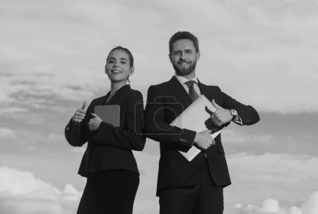 Photo for Portrait of business couple in suit with thumbs up. Two young business workers working together with laptop. Secretary and boss. Business people in suit outdoor - Royalty Free Image