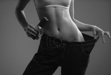 Téléchargez les photos : Skinny waist. Slim woman in oversize jeans, weight loss concept. Diet food, chocolate dieting - en image libre de droit