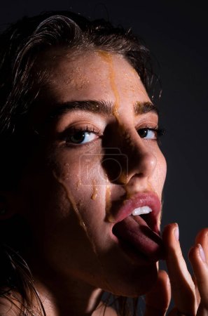 Photo for Sensual young woman face with honey drop close up. Sexy model with honey drip on face. Honey mask - Royalty Free Image