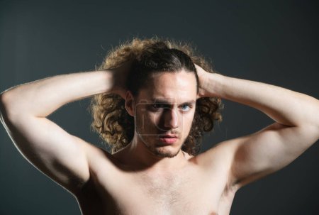 Téléchargez les photos : Jeune homme aux cheveux bouclés. Un bel homme coiffant. Homme avec torse nu nu et cheveux bouclés - en image libre de droit