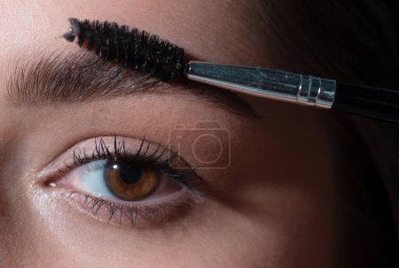 Photo for Eyebrow makeup. Professional care for brows, coloring and lamination. Macro close up of brows. Woman brushing brows with brows brush closeup - Royalty Free Image