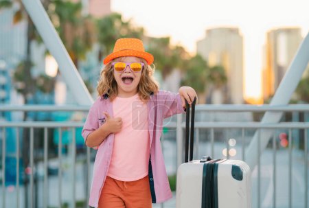 Foto de Niño turista viajero en ropa casual y sombrero con maleta. Niños viajan al extranjero los fines de semana. Concepto de viaje - Imagen libre de derechos