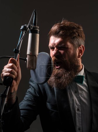 Photo for Singing man in a recording studio. Expressive bearded man with microphone. Classic singer, musical vocalist - Royalty Free Image
