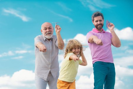 Photo for Men generation: grandfather father and grandson playing with toy plane outdoor on sky. Boy dreams of becoming a pilot. Journey travel trip concept - Royalty Free Image