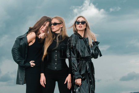 Photo for Fashion portrait of group fashion models girls posing outdoor, black style outfit against sky. Attractive young vogue women. Spring summer collection clothes - Royalty Free Image