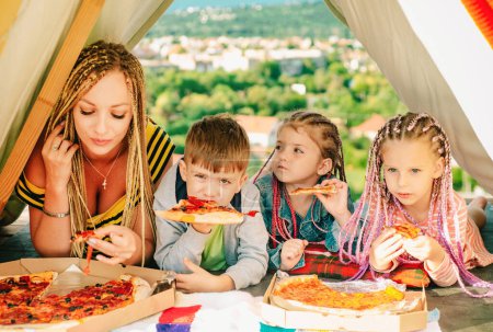 Photo for Family lunch outdoor. Mother with children in tent. Family camping. Mom with kids having fun outdoors. Vacation concept - Royalty Free Image