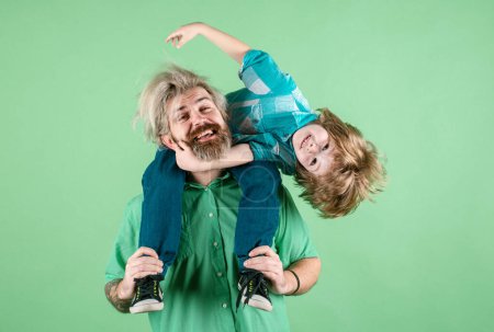 Foto de Happy family. Portrait of happy father giving son piggyback ride on his shoulders. Cute boy with dad in studio - Imagen libre de derechos