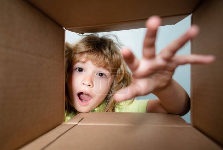 Photo for Child looking inside cardboard box, bottom view. Delivering your purchase. Kids celebrate birthday. Birthday gift. Shocked kids, amazed kids emotions, wow - Royalty Free Image