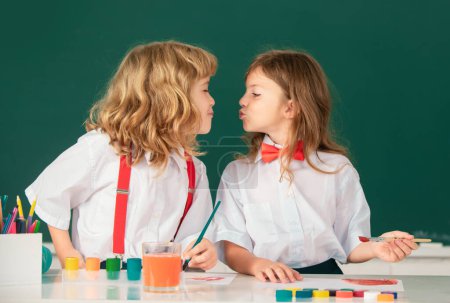 Photo for Cute school friends kids drawing and painting at school. Friendly boy an girl funny pupils kiss. Friendship in school. Best children friends enjoying friendship - Royalty Free Image