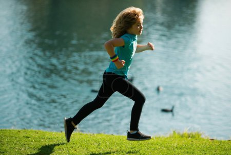 Téléchargez les photos : Les enfants courent dehors. Course et sport sain pour les enfants. Enfant courant sur le terrain d'été près du lac, enfants fitness. Entraînement en cours. Sports de plein air et fitness pour les enfants, exercice à l'extérieur - en image libre de droit