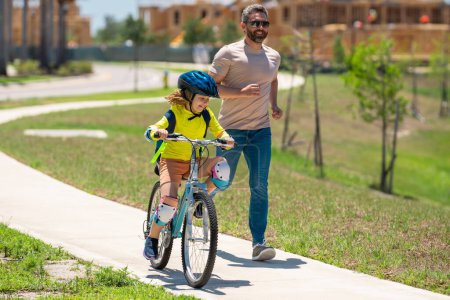Photo for Happy fathers day. Father and son learning to ride a bicycle having fun together at Fathers day. Father teaching his son cycling on bike in american neighborhood. Father and son concept. Father - Royalty Free Image