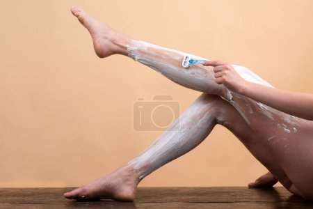Téléchargez les photos : Femme se rase les jambes. Jambes poilues. Femme sexy avec mousse sur la jambe tenir rasoir, et les cheveux rasés sur les jambes. Concepts d'épilation. Femme rasage jambes avec mousse à raser et rasoir. Lond mince sexy jambe féminine - en image libre de droit