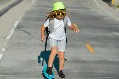 Foto de Niño con monopatín. Tablero de patinaje infantil. Deporte saludable y actividad para escolares en verano. Diversión deportiva - Imagen libre de derechos