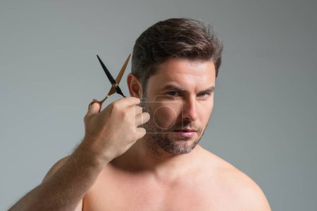 Photo for Caucasian handsome confident man trying to make a hair cut by himself with scissors. Male haircut. Barber scissors, barber shop. Barber scissors. Cutting hair concept. Mens hair style and hair cut - Royalty Free Image