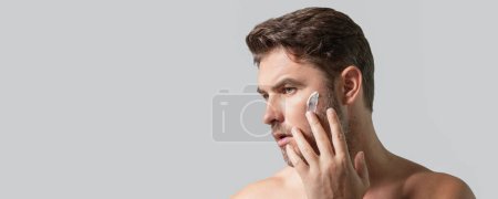 Photo for Mens beauty cosmetics, male beauty and skincare. Morning healthcare and hygiene for man. Perfect beauty skin. Handsome millennial man after shower apply facial cream or mask on skin. Wide banner - Royalty Free Image