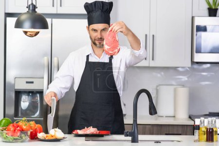 Téléchargez les photos : L'homme attrayant cuisine dans la cuisine moderne. Beau homme cuisinant à la maison préparant la salade dans la cuisine. Homme décontracté préparant la nourriture dans la cuisine moderne. Homme mûr debout dans la table de cuisine, la préparation des aliments - en image libre de droit