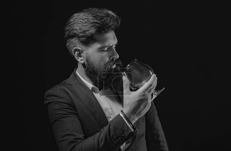 Foto de Hombre barbudo de confianza en traje negro con vaso de whisky en el desván. Hombre seguro y bien vestido con un vaso de whisky - Imagen libre de derechos