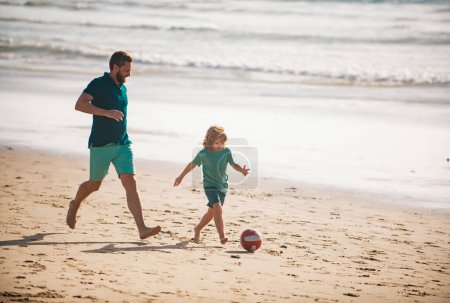 Foto de Papá con niño jugando en un día de verano. Padre e hijo juegan fútbol o fútbol en la playa. Estilo de vida y vacaciones familiares, concepto de hombres de felicidad - Imagen libre de derechos