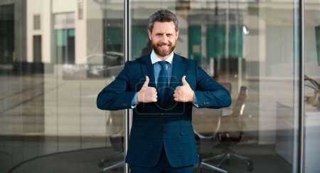 Photo for Businessman giving thumbs up. Business man going thumb up near the office - Royalty Free Image