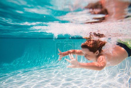 Foto de Niño en piscina en el día de verano. Niño nadando bajo el agua en la piscina. Agua de mar azul. Niño nadando en el mar - Imagen libre de derechos