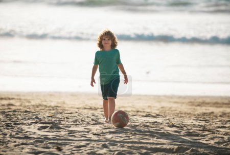 Photo for Little boy child play football on coast of sea beach. Summer kids sports - Royalty Free Image