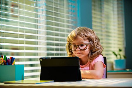 Photo for Smart little boy watch online video lesson at home, small child in glasses have web video class on computer, study at home, homeschooling concept - Royalty Free Image