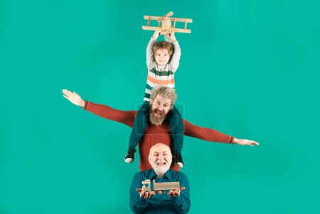 Photo for Three different generations ages grandfather father and child son playing with toy plane in studio. Journey travel trip concept. Isolated background. Men in different ages - Royalty Free Image