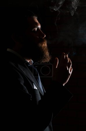 Foto de Hombre fumando cigarrillo aislado en negro. Un hombre fuma marihuana, un porro y un encendedor en sus manos. Humo sobre fondo negro. Conceptos de uso médico de la marihuana y legalización del cannabis - Imagen libre de derechos