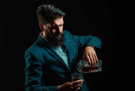 Téléchargez les photos : Hipster avec barbe et moustache en costume boit de l'alcool après la journée de travail. Sommelier goûte boisson alcoolisée coûteuse - en image libre de droit