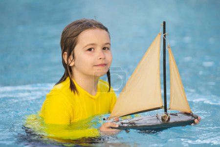 Photo for Little blonde boy put toy boat in the sea waves at the beach during summer vacation. Childhood and summer family vacation. Dream on travel. Travelling tour on sailing ship. Kids dream concept - Royalty Free Image