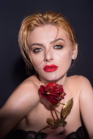 Téléchargez les photos : Slim sexy belle femme avec épaule nue tenir des roses rouges, isolé sur fond de studio. Portrait de fille sensuelle avec des fleurs - en image libre de droit