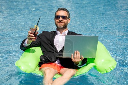 Photo for Summer vacations and freedom travel concept. Portrait of funny business man on the beach. Businessman in suit floating with laptop and cocktail in pool. Crazy business man dreams on summer vacation - Royalty Free Image