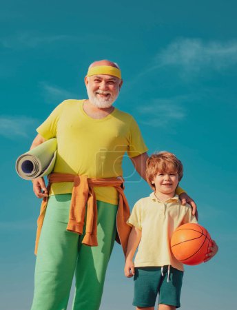 Photo for Rehabilitation. Grandfather and son doing exercises. Senior man and cute little boy exercising on blue sky background - isolated - Royalty Free Image