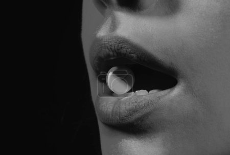 Foto de Suplementos de vitaminas. Cierra la boca de la mujer sosteniendo la píldora en yeeth. Concepto de medicina saludable - Imagen libre de derechos