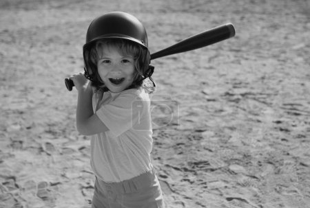 Téléchargez les photos : Portrait du joueur de baseball surpris excité enfant portant un casque et tenir batte de baseball - en image libre de droit