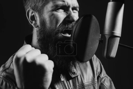 Foto de Cantante con auriculares está interpretando una canción con un micrófono mientras graba en un estudio de música - Imagen libre de derechos