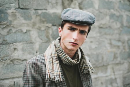 Téléchargez les photos : Jeune homme élégant contre un mur gris. Ancien style rétro et vintage - en image libre de droit