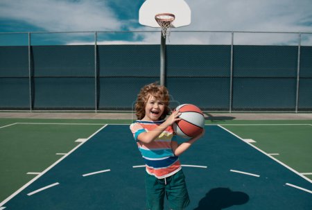 Foto de Niño jugando baloncesto. pequeño caucásico deportes niño jugando baloncesto celebración pelota con feliz cara - Imagen libre de derechos