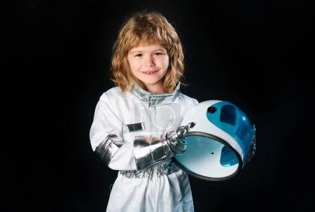 Foto de Lindo niño astronauta niño en traje espacial con casco en el fondo negro - Imagen libre de derechos