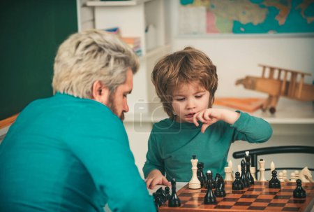 Téléchargez les photos : Bonne famille. Professeur et écolier jouant aux échecs en classe. Développement précoce de l'enfant - en image libre de droit