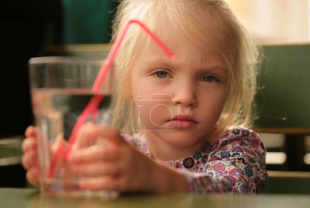 Photo for Portrait of a sweet beautiful baby girl drinking a glass of water - Royalty Free Image