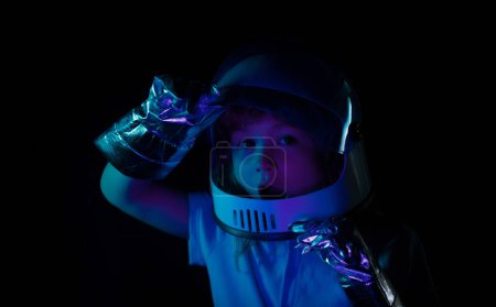 Téléchargez les photos : Portrait de petit astronaute émerveillé en casque et combinaison spatiale de protection. Gros plan enfants excités visage sur la couleur néon - en image libre de droit