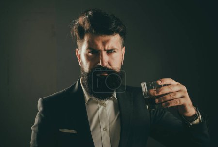 Téléchargez les photos : Élégant homme riche tenant un verre de vieux whisky. élégant élégant barbu homme barman tient verre de whisky - en image libre de droit