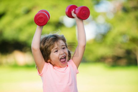 Photo for Excited boy workout in park. Kids sport. Child exercising with dumbbells. Sporty and fitness child with dumbbell outdoor. Kids sport. Kids active healthy lifestyle. Sport portrait kids - Royalty Free Image