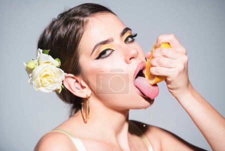 Photo for Closeup portrait of beautiful girl with oranges and colored makeup. Sexy woman with stylish makeup on beautiful face squeezing juice from fresh orange, lick orange juice - Royalty Free Image