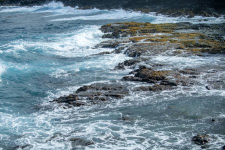 Foto de Lava negra enfriada golpeada por las olas del océano Atlántico. Vista de las olas del mar golpeando rocas en la playa. Olas y rocas - Imagen libre de derechos