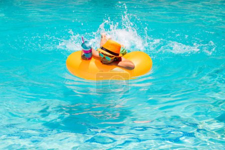 Téléchargez les photos : Enfant d'été dans la piscine. Vacances et loisirs d'été avec les enfants. Concept vacances d'été. Portrait d'enfants d'été avec anneau flottant dans l'eau de mer sur la plage - en image libre de droit