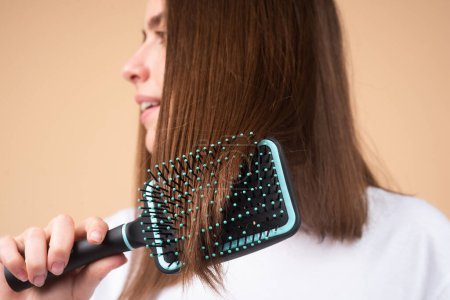 Photo for Close up young beautiful woman combing brown hair. Hair Care. Beautiful brunette woman hairbrushing hair with hairbrush. Brushing healthy hair with comb - Royalty Free Image