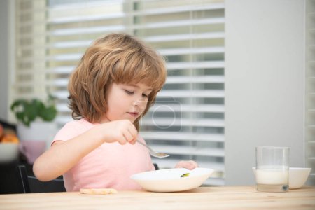 Photo for Child eat. Little healthy hungry boy eating soup from plate with spoon - Royalty Free Image